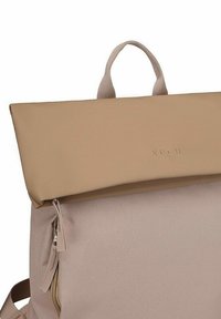 Beige batoh s texturovanou tkaninou, uzávěrem typu roll-top a přední zipovou kapsou. Obsahuje krátké ucho a decentní značkování.
