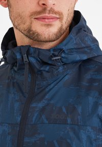 Navy blue rain jacket with a textured pattern, adjustable hood, and front zipper. Features a logo printed on the left chest area.