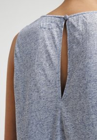 Modrý, melírovaný top s kulatým výstřihem, detaily klíčové dírky na zádech a zapínáním na knoflík. Měkká textura s jemnými barevnými variacemi.