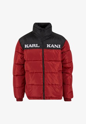 Jachetă puffer roșie și neagră cu guler înalt, cusături orizontale și brandul alb "KARL KANI" pe piept. Închidere cu fermoar, manșete ribbate.