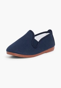 Zapato azul marino sin cordones con parte superior de tela texturizada y suela de goma marrón, corte bajo alrededor del tobillo, visto desde un ángulo frontal lateral.