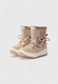 Beige enkellaarsjes met een gewatteerde bovenkant, satijnen afwerking, tonale veters en een dikke witte rubberen zool; heeft een subtiele logo-detail aan de zijkant.