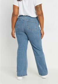 Ljust blå, hög midja denimjeans med en vid ben-design och två bakfickor. Har subtila sömmar och en ren fåll.