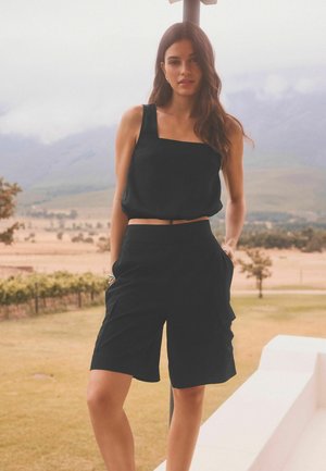 Svart, crop top med fyrkantig halsringning och ärmlös design, matchad med svarta cargoshorts som har sidofickor och en löst sittande passform.