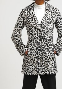 Abrigo de estampado de leopardo en mezcla de lana en blanco y negro, con cuello con muesca, mangas largas y bolsillos laterales.