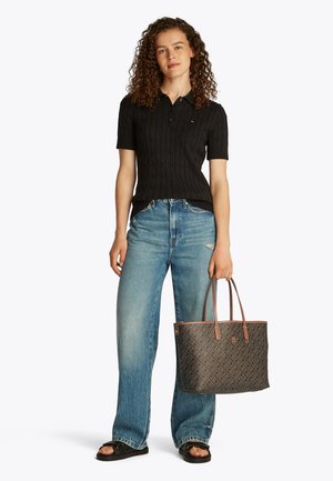 Sort kabelstrikket poloshirt, lyseblå vidbenede jeans, brun mønstret tote-taske og sorte slidesandaler. Casual outfit med teksturerede detaljer.