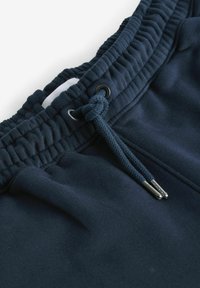 Navyblaue Sweatpants verfügen über einen elastischen Bund mit Kordelzug, metallischen Ösen und einer glatten, weichen Stofftextur.