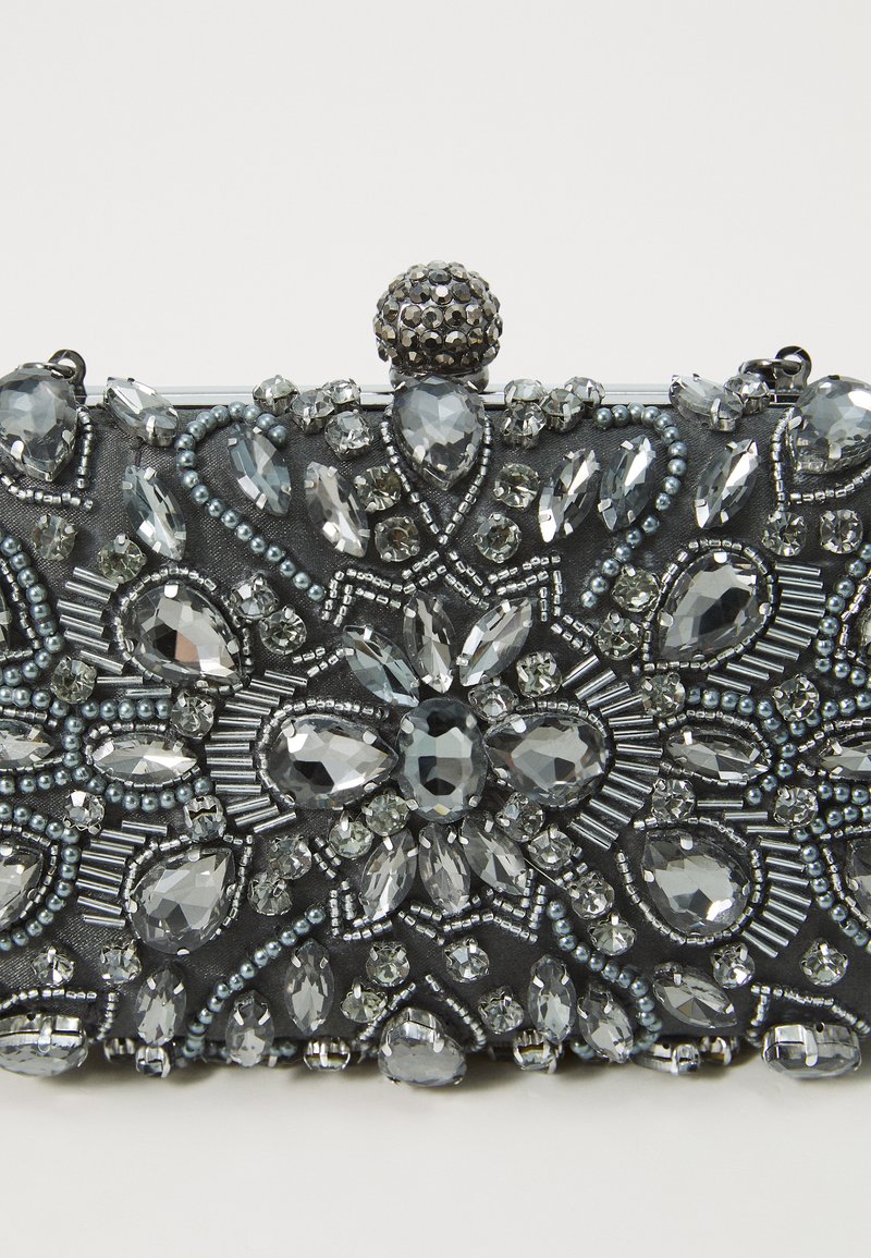 Kopertówka z koralików z ciemnoszarym tłem, ozdobiona różnej wielkości przezroczystymi kryształkami i srebrnymi koralikami, zwieńczona ozdobnym zapięciem.