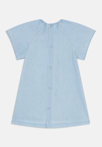 Lyseblå kjole laget av denim med korte raglanermer, rund halslinning og knappelukking bak. Glatt tekstur, ingen synlige mønstre.