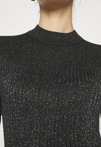 Czarny prążkowany sweter z wysokim kołnierzem, o fakturowanej powierzchni z subtelnymi, wielobarwnymi metalicznymi nitkami.