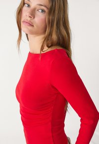Rode langemouwen top gemaakt van rekbare stof, met een slim fit, ronde halslijn en geplooide zijnaden.