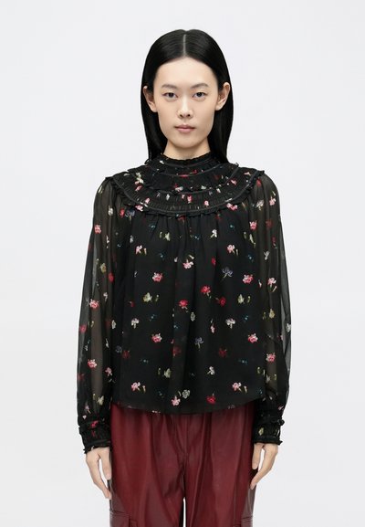 Blouse noire transparente à motifs floraux, col volanté et poignets froncés. Coupe ample avec manches longues.