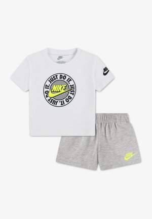 Camiseta blanca de Nike con logo neón y texto "Just Do It", combinada con pantalones cortos Nike grises con cinturilla elástica y logo neón.