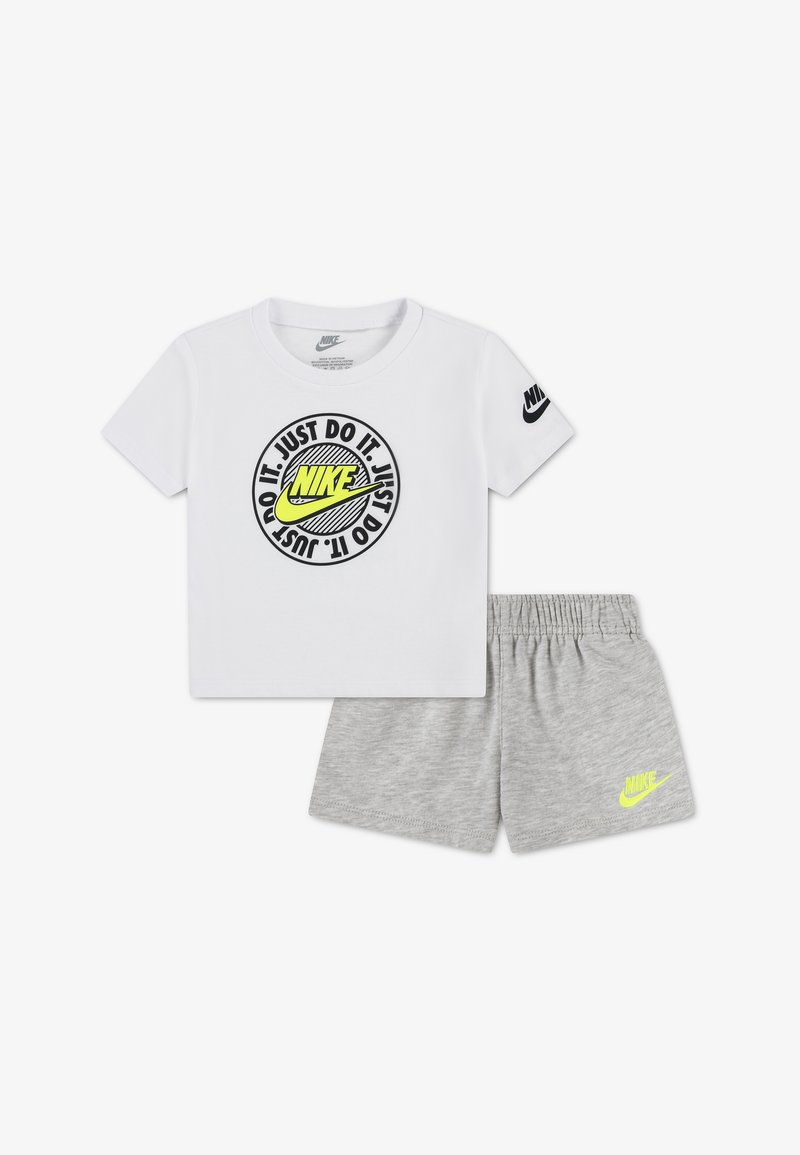 Λευκό T-shirt της Nike με νεον λογότυπο και το κείμενο "Just Do It", συνδυασμένο με γκρι σορτς με ελαστική μέση της Nike και νεον λογότυπο.