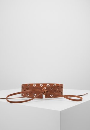 Ceinture en cuir marron avec des motifs floraux ajourés et un nœud noué à l'avant, présentée sur une surface blanche avec un fond uni.