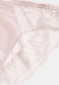 Lichtroze satijnen slip met bloemenkant afwerking, zachte textuur, golvende randen en een klein label met "Rosie" op de tailleband.