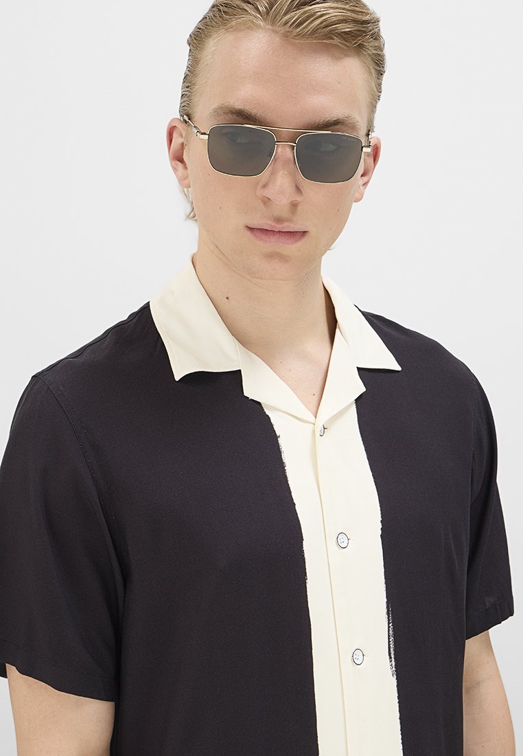 Kurzarmhemd mit schwarzem Körper und krämfarbener Kragen- und Knopfleiste. Verfügt über Knöpfe und ein kontrastierendes vertikales Streifendesign.