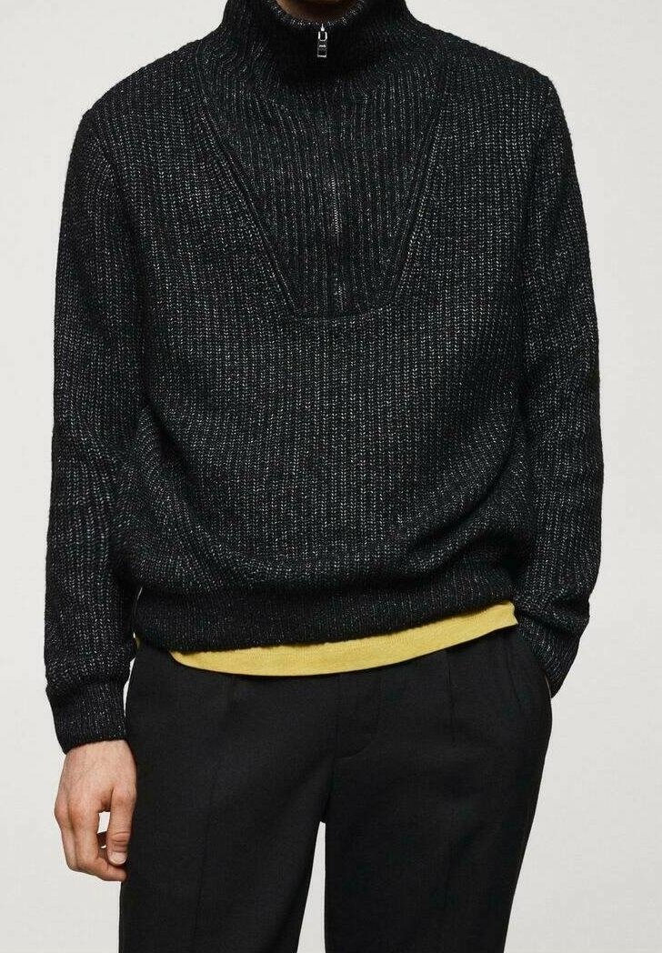 Schwarzer Strickpullover mit hohem Kragen und halbem Reißverschluss, der aus strukturiertem Material gefertigt ist und über einem gelben Hemd einen Lagenlook präsentiert.