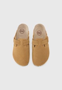 Brązowe zamszowe klapki typu slip-on z okrągłym noskiem, podwójnymi paskami i miękką podszewką wewnętrzną. Podeszwa ma teksturowany design dla lepszej przyczepności.
