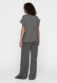 Top grigio, ampio e comodo, con maniche corte e un design rilassato, abbinato a pantaloni larghi coordinati, entrambi in morbido materiale jersey.