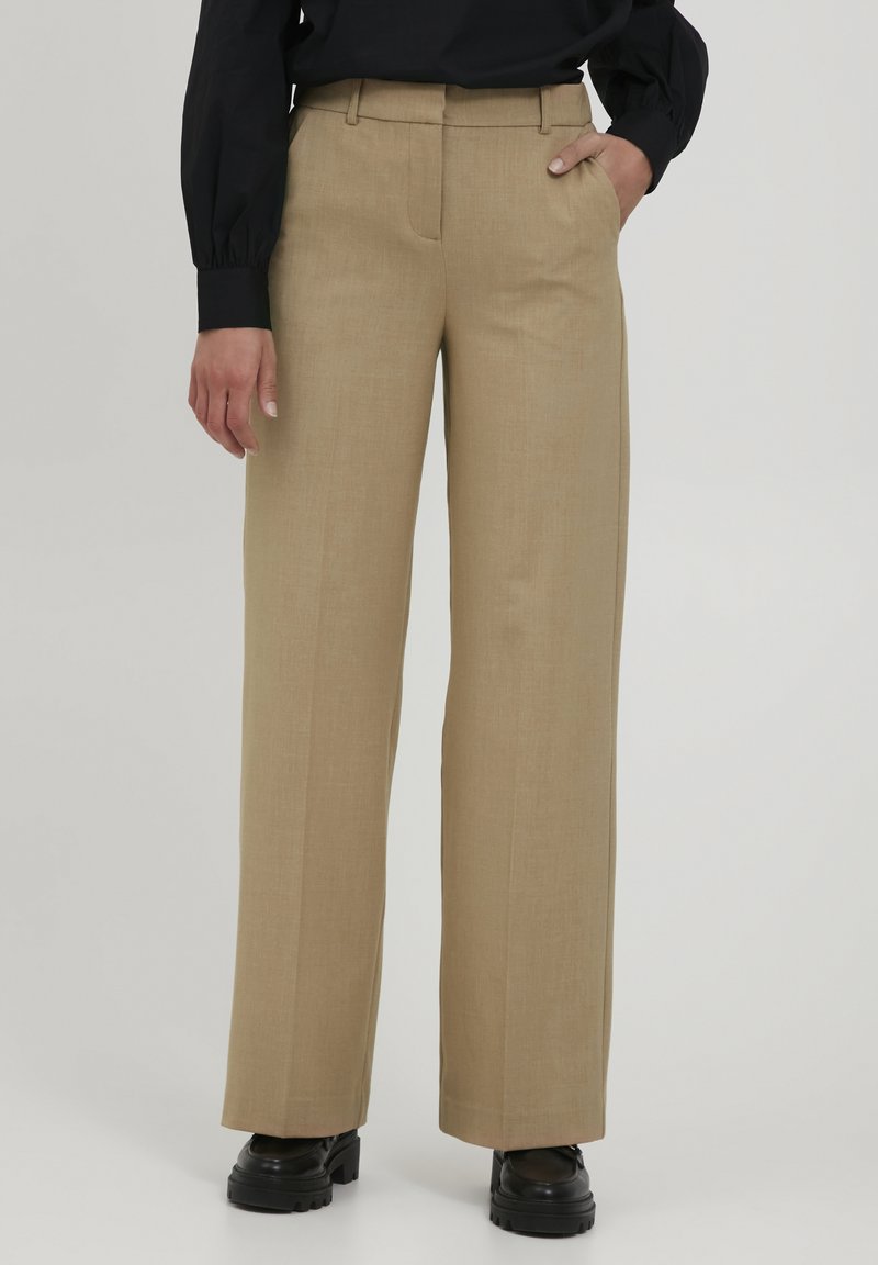 Beige weit geschnittene Hosen aus leichtem Stoff. Sie haben eine glatte Textur, Falten an der Vorderseite und seitliche Taschen.
