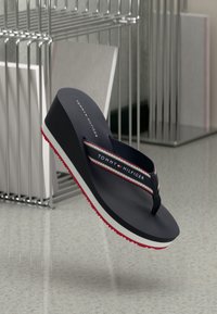 Navy flip-flop with a wedge, featuring a white and red striped band, textured black footbed, and a red-accented sole.