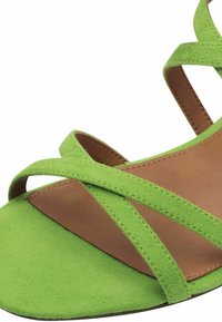 Vihreät mokkanahka-sandaalit, joissa on tasapohja, ristiin meneviä hihnoja ja ruskea nahkasisus. Yksinkertainen muotoilu, jossa on sileä pinta.