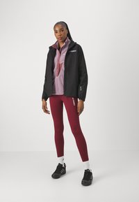 Black waterproof jacket, light purple fleece half-zip shirt, maroon leggings, and black athletic shoes with white accents.