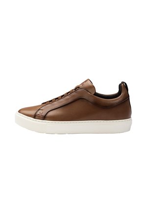 Lage bruine leren sneaker met witte rubberen zool en zwarte binnenvoering, met een treklus op de hiel en gestikte details.