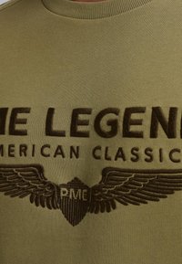 Olive zelená mikina vyrobená z jemnej látky, s hnedým vyšitým textom "THE LEGEND" a emblémom s krídlami s nápisom "RME." S okrúhlym výstrihom.