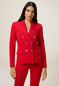 Czerwony żakiet dwurzędowy z srebrnymi guzikami, z wykładanym kołnierzem, dwoma przednimi kieszeniami, dopasowany krój, wykonany z gładkiego materiału.