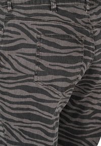 Jeans de denim gris con un patrón de rayas de cebra negras, con un bolsillo trasero estándar y detalles de costura visibles.