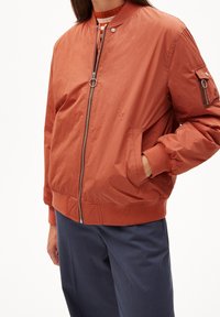 Bomber arancione in tessuto leggero con chiusura frontale a zip, polsini e orlo a costine e tasca con zip sulla manica.