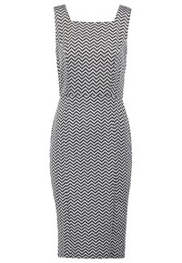 Svartvit klänning med zickzackmönster, fyrkantig halsringning och figursydd silhuett, tillverkad av stretchigt tyg för en åtsittande passform.