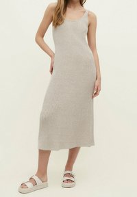 Robe maxi en tricot côtelé gris clair avec un col rond et de larges bretelles, complétée par des sandales à plateforme blanches avec deux accents de boucle.