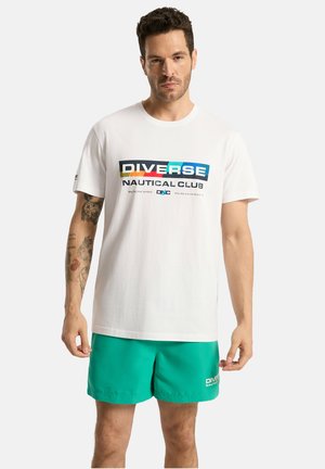 Biała bawełniana koszulka z kolorowym nadrukiem "DIVERSE NAUTICAL CLUB". Połączona z turkusowymi szortami. Prosty, casualowy design.
