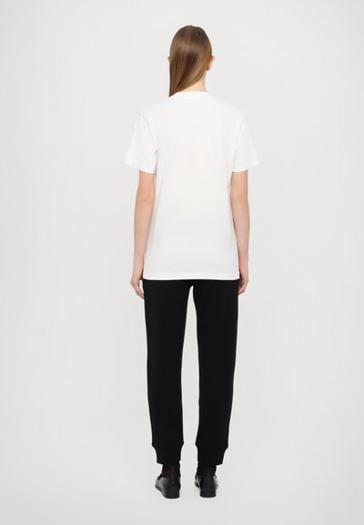 Hvit bomull t-skjorte med korte ermer, paret med svarte joggebukser med ribbede mansjetter. Enkel og funksjonell design.