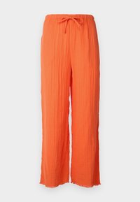 Pantalons orange à coupe décontractée en tissu texturé, avec une taille réglable par cordon et des ourlets effilochés, conçus pour le confort et la respirabilité.