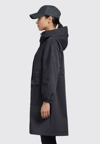 Tmavá, nepremokavá parka so sťahovacou kapucňou, elastickými manžetami a dvoma prednými vreckami. V páre s rovnakou čiapkou, ktorá zdôrazňuje elegantný siluetu.