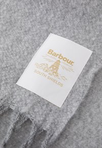 Halljane fliiskangas, millel on valge silt kuldsete tähtedega, kus on faarvaatri graafika ja sõnad "Barbour" ja "SOUTH SHIELDS."