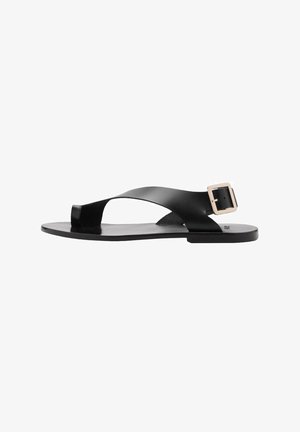 Zwarte platte sandalen met een kruisbandontwerp, gemaakt van soepel materiaal. Voorzien van een vierkante gespsluiting op de enkelband en een minimalistische zool.