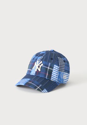 Casquette de baseball patchwork bleue avec le logo blanc des New York Yankees brodé sur le devant et divers motifs à carreaux et rayures.
