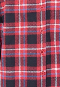 Rød og marineblå ternet flannel skjorte med hvide og blå detaljer, prydet med røde knapper foran. Blød tekstur, struktureret mønster.