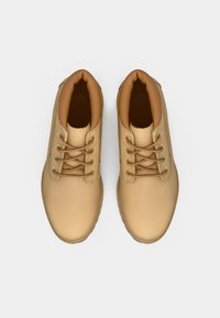 Brune høyhælte sko med glatt lær overdel, rund tå og brun polstret krage. Utstyrt med metalløyler og snørebånd. Minimalistisk design.