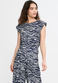 Top w navy i białą zebra w paski, z krótkimi, podwiniętymi rękawami i wcięciem w pasie, wykonany z miękkiego materiału o gładkiej fakturze.