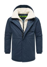 Marinblå jacka med en fuskpälsfodrad huva, framzipper, två sidofickor och ribbade ärmslut. Har en logotyp på ärmen.