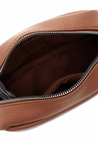 Interno di una borsa a mano in pelle marrone con chiusura a zip, fodera morbida e una piccola tasca per l'organizzazione. Materiale testurizzato visibile.