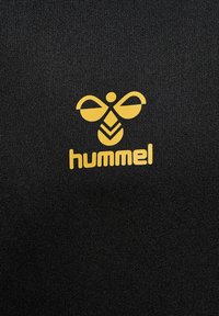 Tessuto nero con una texture liscia caratterizzato da un logo Hummel giallo, che rappresenta un design stilizzato di un'ape insieme al nome del marchio in basso.