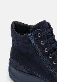 Bottines en daim bleu marine avec une surface texturée, doté d'une fermeture éclair sur le côté, de lacets ronds et d'une semelle rembourrée.