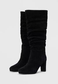 Bottines en suede noir avec un design flou, talons carrés et texture lisse. Présentent une forme de bout arrondi et des détails de couture minimalistes.